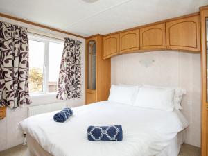 a bedroom with a large white bed and a window at Bwthyn Y Bae Lodge in Holyhead
