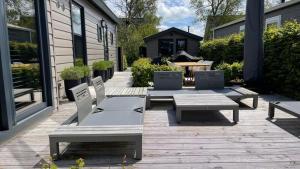 een patio met twee banken en een tafel en een tafel en stoelen bij PUUR Eernewoude luxe chalet direct aan open vaarwater gelegen in de Alde Feanen in Earnewâld