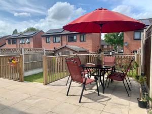 a table and chairs with a red umbrella on a patio at Maya Boutique Inn - Garden - Sleeps 6 in Wythenshawe