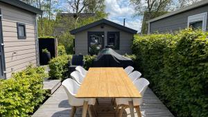 een houten tafel en stoelen in een achtertuin met een huis bij PUUR Eernewoude luxe chalet direct aan open vaarwater gelegen in de Alde Feanen in Earnewâld