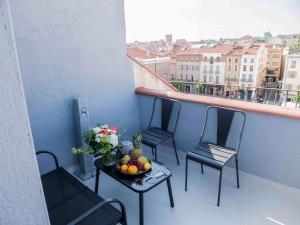 2 chaises et une table avec un bol de fruits sur le balcon dans l'établissement Suites Coronell d'En Vila, à Perpignan