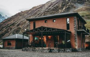 a large brick house with a mountain in the background at Kazbegi Mountains in Kazbegi