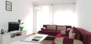 een woonkamer met een rode bank en een tv bij Apartment Vasilije in Žabljak