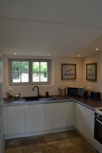 a kitchen with white cabinets and a sink at L'Orangerie, Château St Justin in Saint-Justin