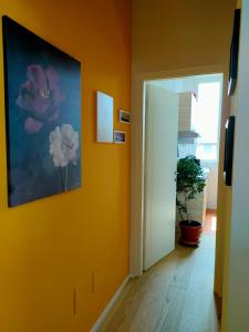 een hal met een oranje muur met een schilderij van bloemen bij MonoPat in Marina di Pisa