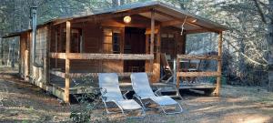 une cabane en bois avec deux chaises et une table dans l'établissement Domaine de la Vitarelle Glamping, à Villanière