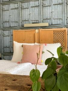 uma cama com almofadas brancas e cor-de-rosa e uma planta em Hotel Au Nom De Dieu em Dilsen-Stokkem
