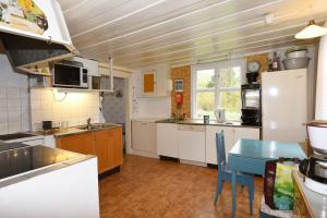 une cuisine avec des placards blancs et une table bleue dans l'établissement Idyllic holiday house in Sundshult, à Bullaren