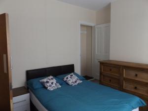 a bedroom with a blue bed and a wooden dresser at MountCastle House in Leicester