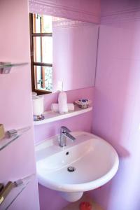 un lavandino bianco in un bagno rosa con finestra di The Little House Corfu ad Áno Korakiána