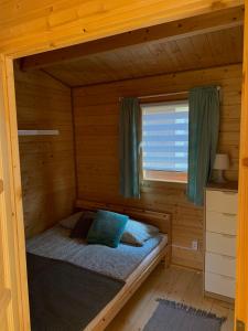 łóżko w drewnianym domku z oknem w obiekcie Domki u Oli w Stegnie
