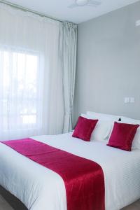 a bedroom with a large bed with a red blanket at Kiki's @ Palm Ridge-Vipingo in Kilifi