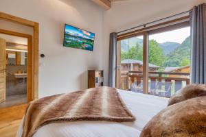 ein Schlafzimmer mit einem Bett mit einem großen Fenster in der Unterkunft Chalet Paradis Blanc Morzine in Morzine