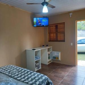 - une chambre avec un lit et une télévision murale dans l'établissement Suites Chacara Madu, à Santo Antônio do Pinhal