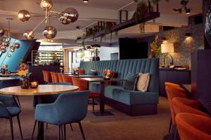 un restaurante con sofá azul, mesas y sillas en Van der Valk Drachten en Drachten