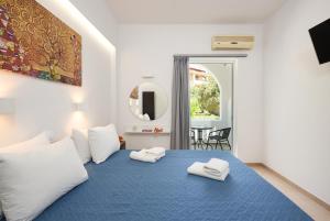 a bedroom with a blue bed with two towels on it at Afroditi Hotel in Plakias