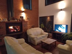 ein Wohnzimmer mit 2 weißen Stühlen und einem TV in der Unterkunft La Mexicana - Alta Gracia in Alta Gracia
