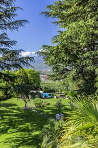 a green park with trees and a lake in the distance at Villa Eden a member of Leading Hotels of the World in Merano