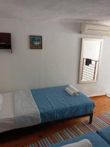 a bedroom with a bed with a blue blanket and a window at VILLA SISSY in Agia Paraskevi
