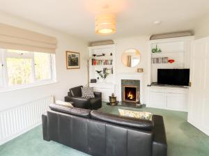 a living room with a leather couch and a fireplace at The Cedars in Ambleside