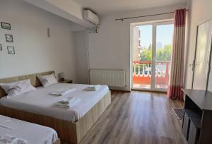 a bedroom with two beds and a large window at Casa Tatiana Eforie Nord in Eforie Nord