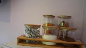 a shelf with four glass jars with food in it at Habititabities in Tenby