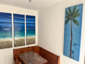 a room with three paintings of the ocean and a table at AppArt 21 in Lignano Sabbiadoro