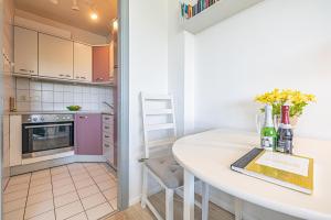 a small kitchen with a white table with flowers on it at fewo1846 - Del Mar - komfortable 2-Zimmer-Wohnung mit Balkon im 7 OG in Glücksburg