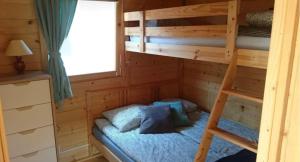 a bunk bed in a wooden cabin with a ladder at Domki u Oli in Stegna
