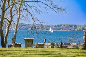 a sailboat on a lake with a fence and a tree at fewo1846 - Sonne und Meer - kleines Studio-Apartment mit Balkon und Meerblick in Glücksburg