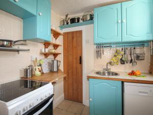 a kitchen with blue cabinets and a sink at Poppy Cottage in Swanage