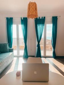 a living room with a couch and a laptop on a table at Αλός αήρ suites in Kithnos