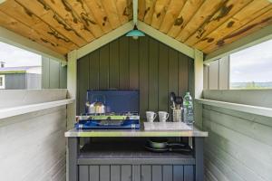 an outdoor kitchen with a stove in a shed at Moss Shepherd's Hut by Bloom Stays in Egerton
