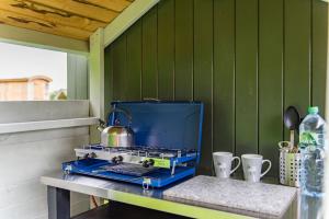 a stove with a tea kettle and cups on a table at Moss Shepherd's Hut by Bloom Stays in Egerton