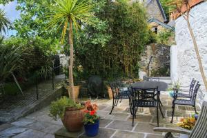 een terras met een tafel, stoelen en planten bij Gargoyle Cottage in St. Agnes 