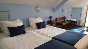 a bedroom with two beds with blue and white pillows at Hospedaria 5 Bicas in Aveiro