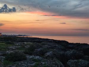 una puesta de sol sobre una playa con rocas y el océano en La Casa di Clé, en Fasano
