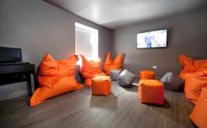 Cette chambre dispose de chaises orange et d'une télévision à écran plat. dans l'établissement Sleeperdorm, à Newcastle upon Tyne