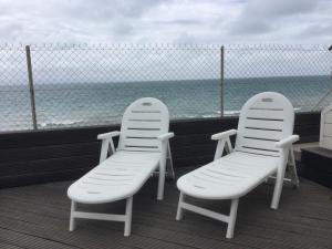 2 weiße Stühle auf einem Balkon mit Meerblick in der Unterkunft COMME SUR UN BATEAU FACE À LA MER in Agon Coutainville