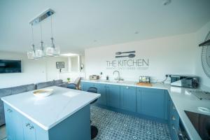 a kitchen with blue cabinets and a white counter top at 'The View' Penthouse Apartment Number Four Lees Terrace in Holt