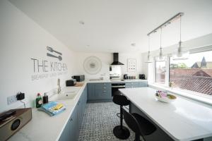 uma cozinha branca com armários azuis e um lavatório em 'The View' Penthouse Apartment Number Four Lees Terrace em Holt