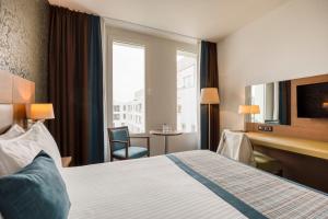 Habitación de hotel con cama, escritorio y ventana en Leopold Hotel Oudenaarde en Oudenaarde