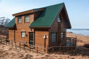 una casa de madera con techo verde en una colina en Vindheimar Cottage - Great View - Hot Tub, en Skeljabrekka