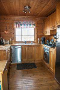 a kitchen with wooden cabinets and a sink and a window at Vindheimar Cottage - Great View - Hot Tub in Skeljabrekka