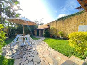 un patio con 2 sillas y una sombrilla en Casa dos Carijós, en Ilhabela