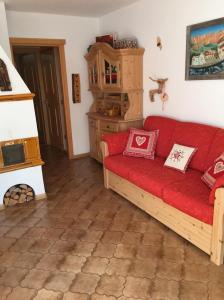 ein Wohnzimmer mit einem roten Sofa und einem Herd in der Unterkunft Brunetti in Mazzin
