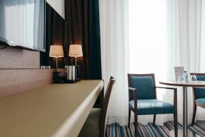 een hotelkamer met een bureau en een tafel en stoelen bij Leopold Hotel Oudenaarde in Oudenaarde