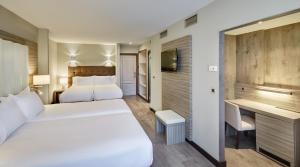 a hotel room with two beds and a television at Gran Hotel Luna de Granada in Granada