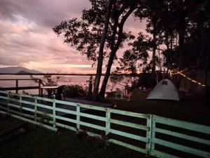uma cerca branca e uma tenda ao lado de um lago em Camping Mirante dos Golfinhos em Cananeia