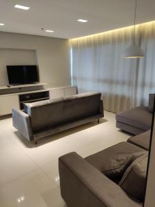 a living room with a couch and a flat screen tv at Flat encantador Slaviero Complexo Heron Marinho in Campina Grande